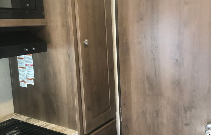 Pantry next to stove top and microwave