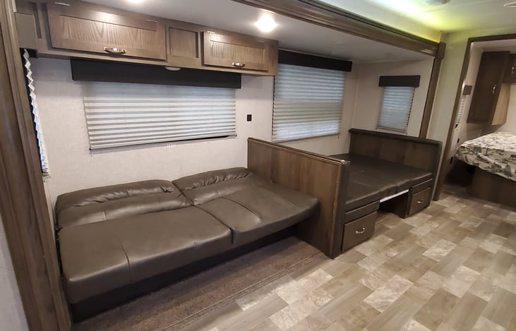 Two full size beds by night. Couch features storage cabinets above and large storage underneath so all luggage can be stashed away.