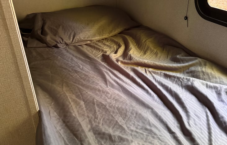 The bunk bed access is across from the pantry. The bottom bunk has a window with a shade and a dome light.