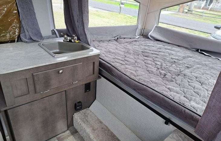 View of one sleeping area, the sink, and the refrigerator.