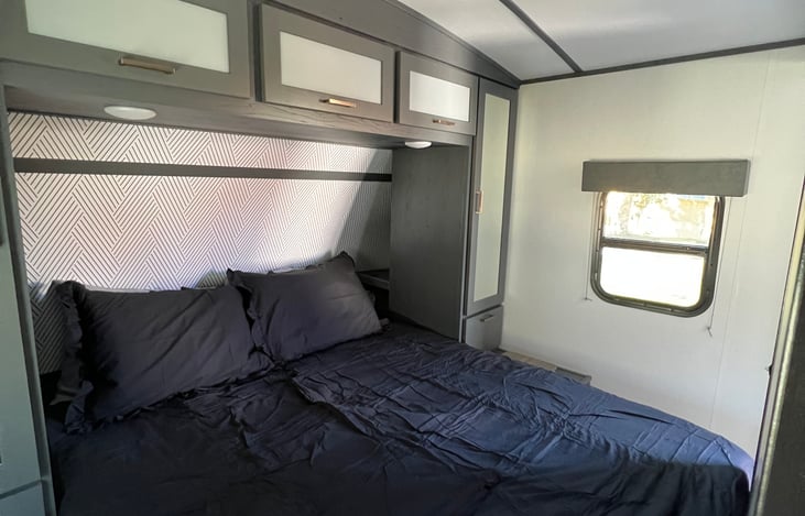 Queen sized bed with bedding and dual closets. Overhead storage.