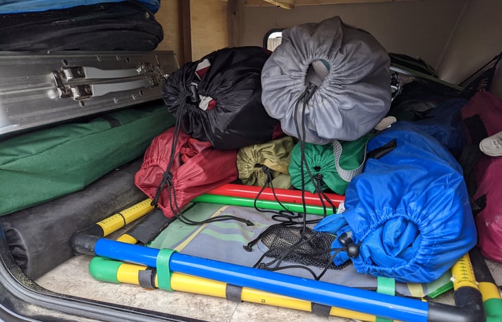 Outside storage compartment includes 4 adult size camp chairs, 2 child camp chairs, camp table, pop-up trash can, patio mat with stakes, and outdoor games. Outdoor games vary.