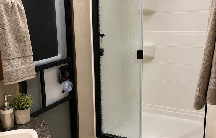 Bathroom with a secondary exterior door. The shower is large and tall.