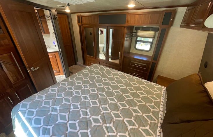 Primary bedroom with queen bed featuring wardrobe & drawers.