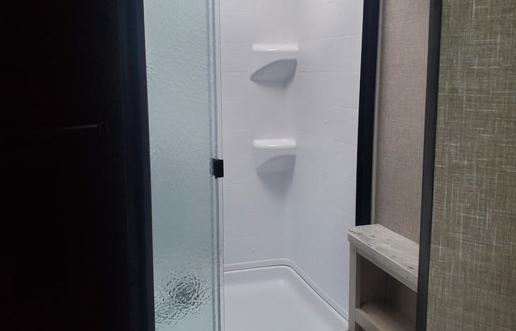 Wide shower has a slide door, must secure with latch that must be attached before transport.