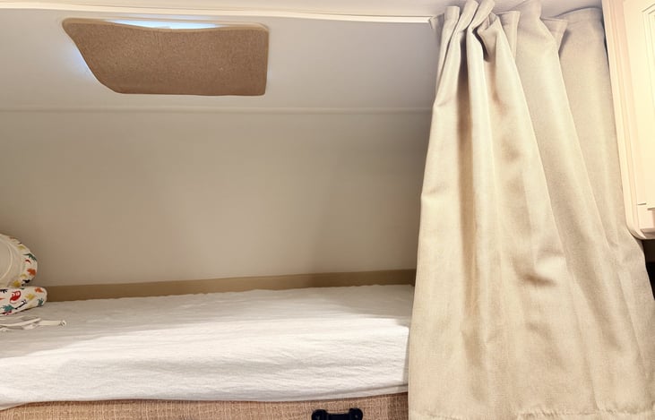Cab-over bunk with privacy curtain; bedding included