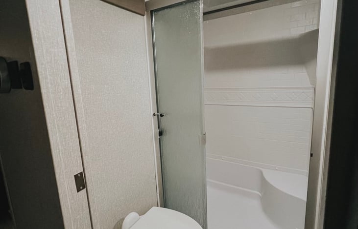 First bathroom with shower, glass door and skylight natural light.