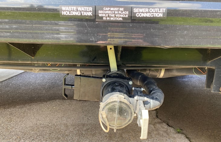 Left side of RV: Grey and black tank outlets- (hoses for tanks kept in container in side storage)