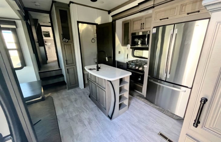 Spacious and bright chef's kitchen with island. Ample storage throughout. Hardwood cabinetry, solid-surface countertops, and residential fridge.