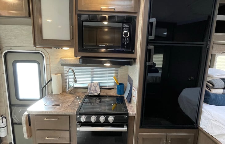 Modernkitchen, stainless steel sink with pulldown sprayer, microwave, three burner gas stove with glass top. Refrigerator and freezer with glass paneling.