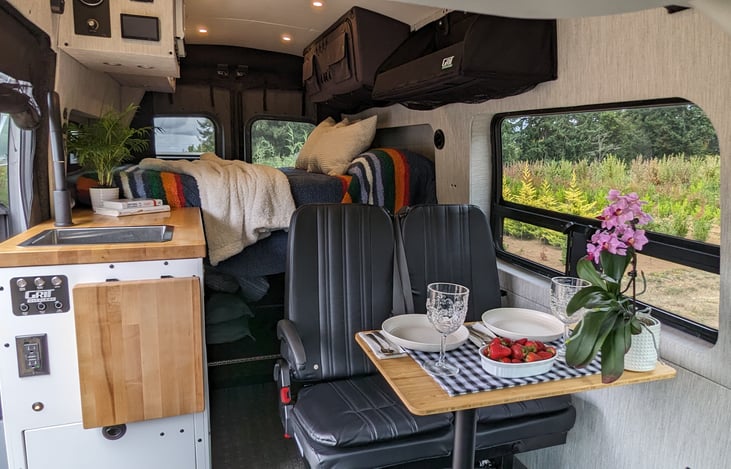 Inside the van, a fold-up/down bench seat and fold-away Murphy bed with built-in table create a flexible space—great for dining, working, or relaxing after a day of exploring.