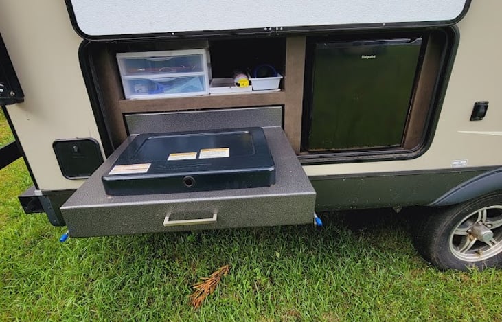 Outdoor kitchen with storage area, 2 burner cooktop and refrigerator.