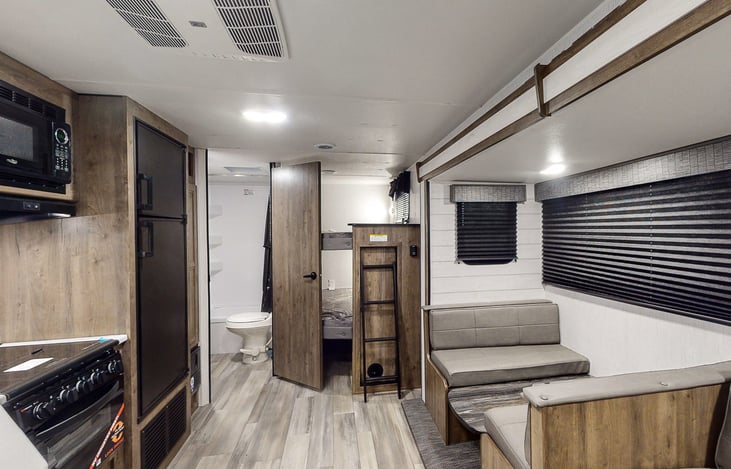 Two Bunk Beds, Dinning Area, Bathroom with toilet and shower. Sink has storage above.