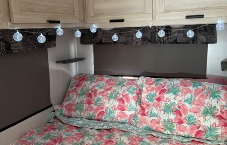 Queen sized bed with bedside shelves and disco ball twinkle lights.