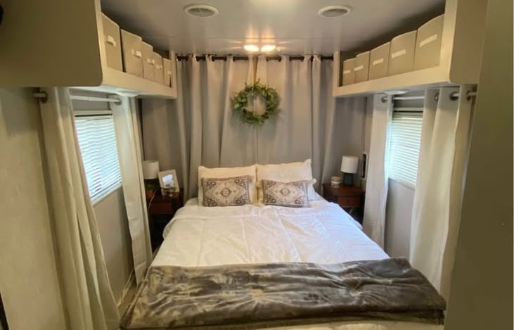This is the cargo area bedroom. The bed frame folds up & can be stored on the side to allow cargo to enter through the door that's behind the curtain. Threr's a pull down screen over the cargo door