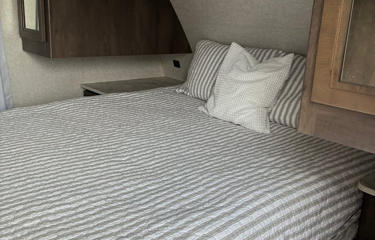 The primary bedroom is a private bedroom with a sliding door and a queen-size bed. Nightstands with drawers, USB ports, and electric outlets on each side of the bed. Closets and cabinets, too.