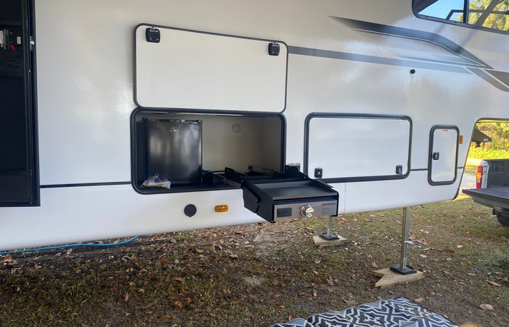 Outdoor kitchen with refrigerator and griddle.