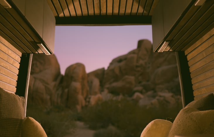 Transition seamlessly from a comfortable lounge space to a soft, cozy queen‑size bed, layered with fluffy throw pillows and a warm blanket ideal for unwinding under the open sky