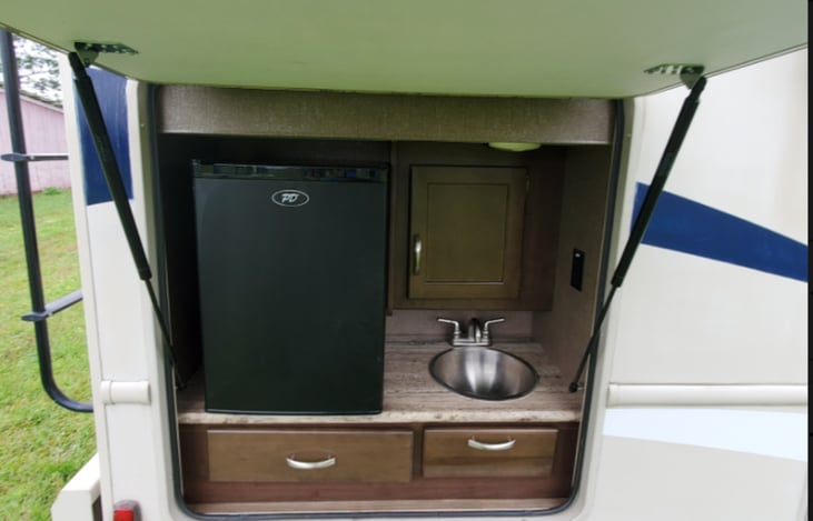 Exterior kitchen equipped with refrigerator and sink