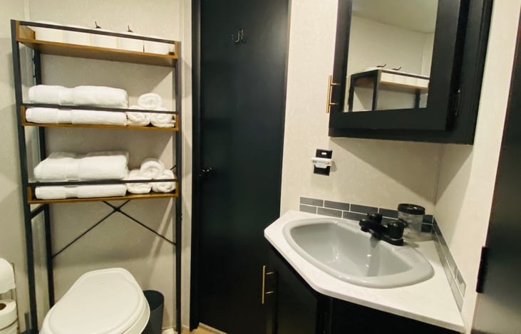 The bathroom has triple-entry access from the main bedroom, hallway, and outside door. Fully stocked with towels, cleaning supplies, complimentary shower toiletries, a hair dryer, and toilet paper.