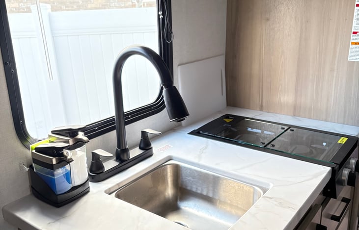 High rise pull-down faucet, sink, soaps and sponge.