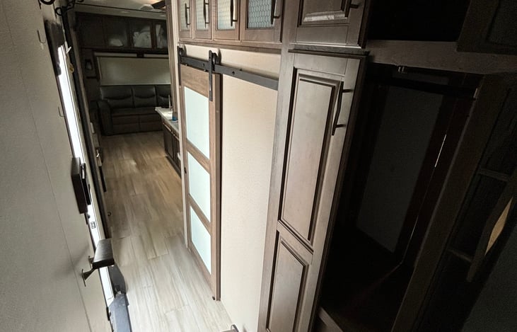 view from top of hallway looking into living room. On the right is the door to the second bedroom as well as a coat closet and storage