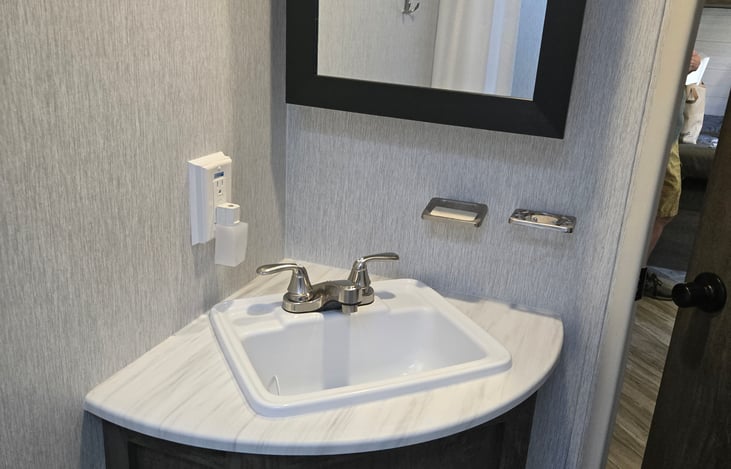 Bathroom sink with vanity, undersink storage, soap holder, and toothbrush holder.
