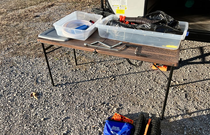 Clean water hose, spay nozzle, hose splitter and pressure valve, jack levels, sewer hoses and sewer hose riser and stabilizer jack tool, folding table all included in utility side storage area