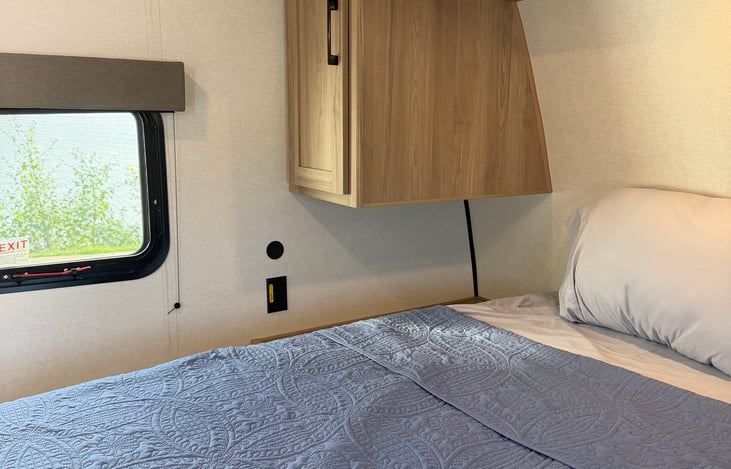 Restful master bedroom suite equipped with a comfortable queen bed, overhead storage cabinets, and warm ambient accent lighting.
