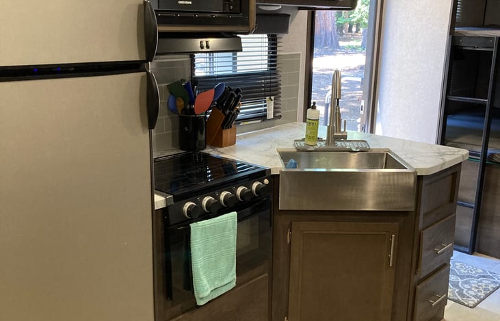 Kitchen with sink, oven, stove, microwave, fridge, freezer, and pantry.