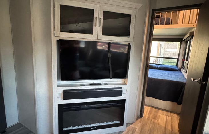 Tv, Fireplace, Sound-bar. Walkie-Talkies are located in the cabinets above the TV. Bunk House entrance to the right