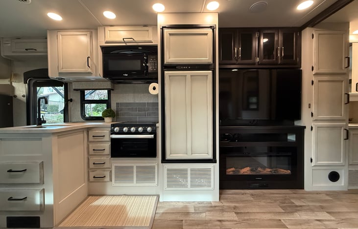 kitchen area with sink, oven, microwave, fridge/freezer next to the entertainment area with cozy fireplace