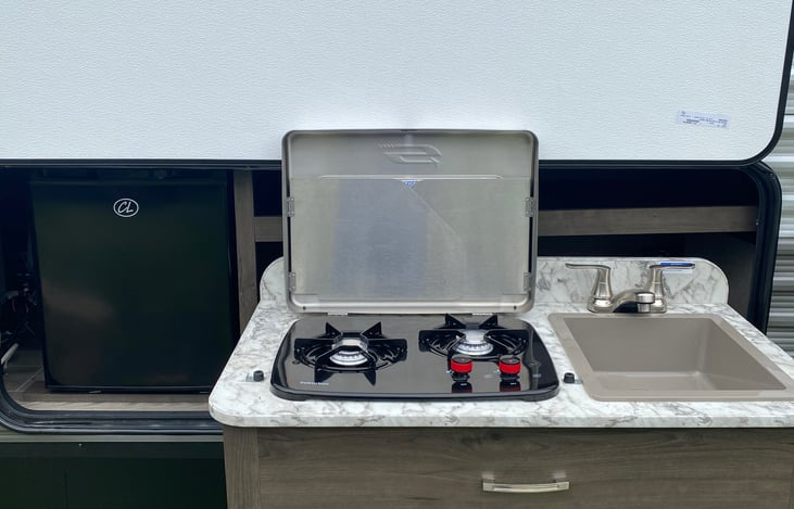 Outdoor kitchen. Hot and cold water sink. 2 gas burner stove. And small size refrigerator.