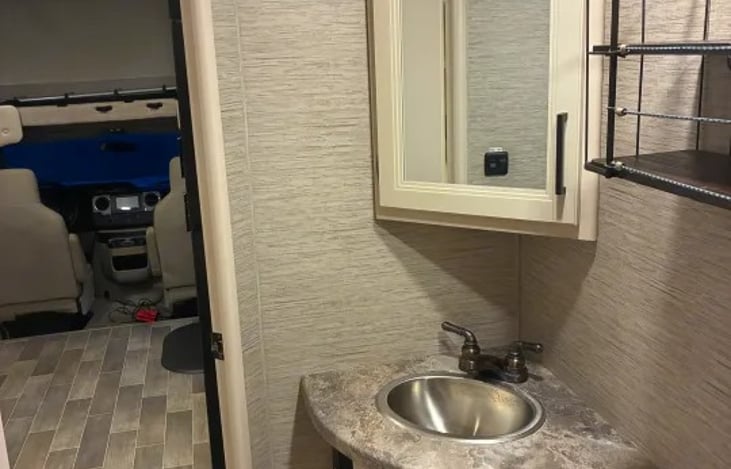 Private rear corner bathroom has a foot-flush toilet, and a counter sink with medicine cabinet.