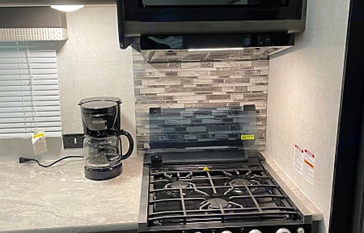 Three burner cooktop with oven and microwave above stove.
