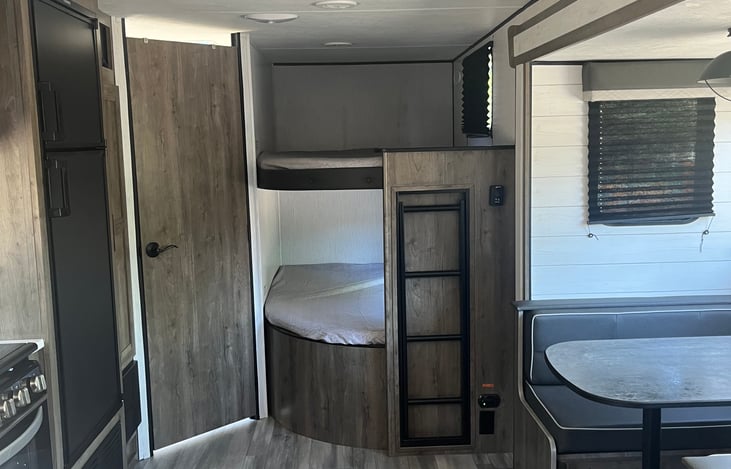 Bunk bed ladder can be pulled out to climb up, and stored vertical during the day to avoid trip hazard. Night lights in each bunk as well as windows with sleeping shade.