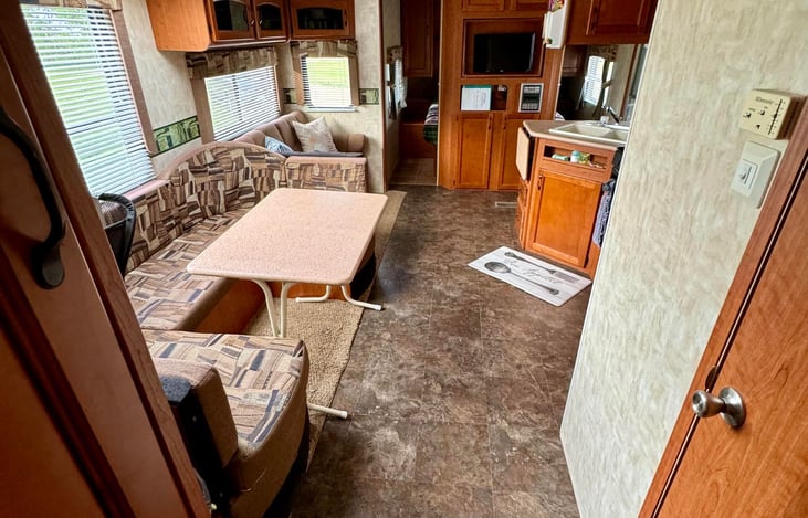 View from the back bedroom area into the main living space. Dinette area converts to a bed with the table sliding into the open space. Bedding stored in the pull out drawers beneath the dinette.