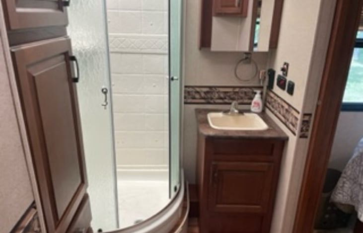 Bathroom with shower, sink, cabinets, and ceramic toilet.