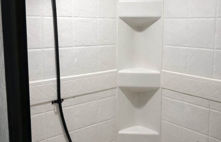 Modern shower with stylish black fixtures and built-in shelving for convenience.