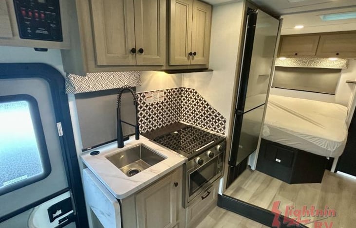 3-burner gas range under glass top which is used to provide more prep space, sink, storage cabinets and a combination microwave/convection oven.