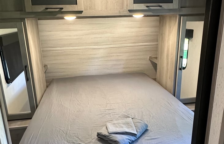 Queen bed with ample storage that surrounds it. Power outlets on both sides with a double shelf night stand.