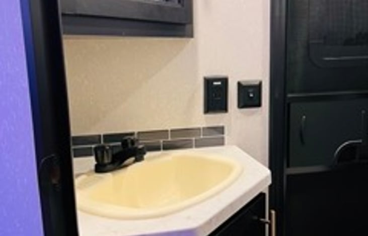 Bathroom sink and medicine cabinet stocked with travel size toiletries, towels, and blow dryer for your conveience