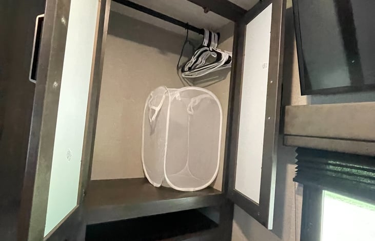 Closet with hangers and hamper.