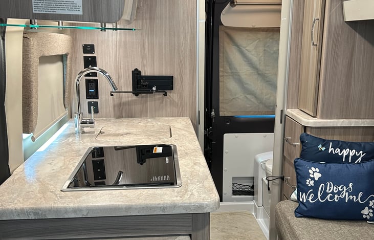 Entry area with kitchen and seating to the right the seating pulls out into a full size bed.  With wet bath door open in the back