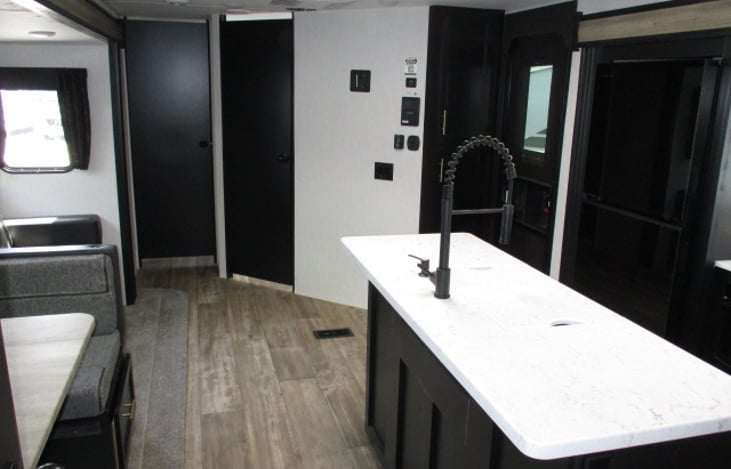 looking forward to bathroom and bedroom area, with couch to left and outside door to right