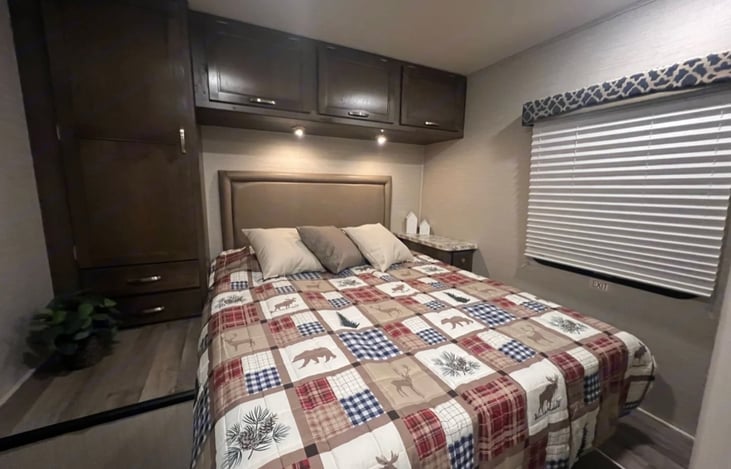master bedroom with queen walk around bed, lots of storage and tv