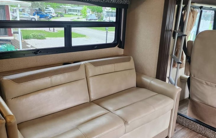 Couch seating with storage under.  Ladder on wall behind back rest for bunk.