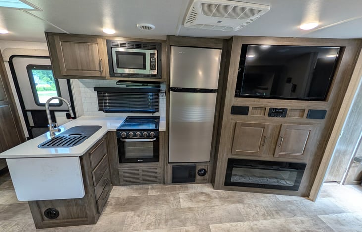 Spacious open-concept living area w/ dual recliners, TV & fireplace. Full kitchen features a residential fridge, 3-burner stove, oven, microwave, deep sink & booth dinette! Natural light throughout.