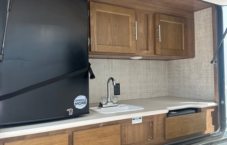 An outdoor mini refrigerator, sink, and cabinets for added convenience.