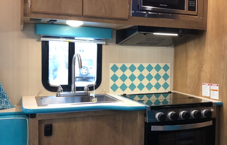 Partial kitchen view - sink, microwave, and stove on one side (and refrigerator is across)